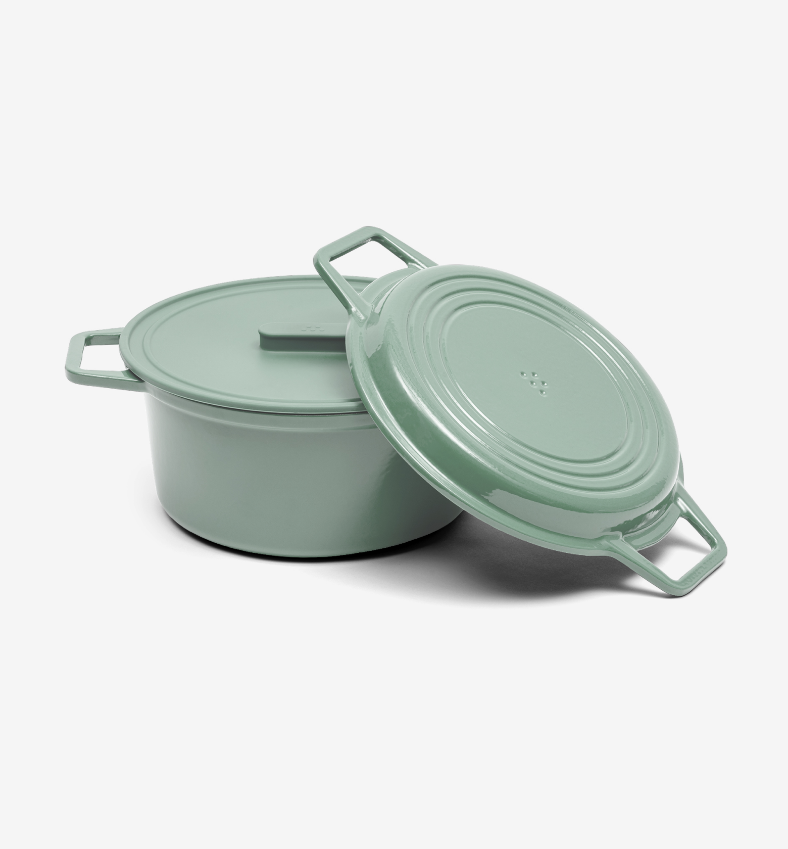 Sage green enameled cast iron Dutch oven with lid leaning against pot